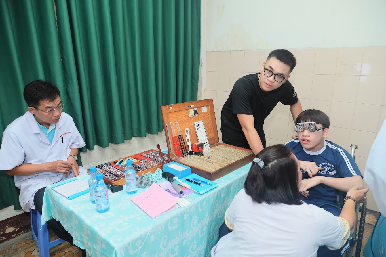 Bác sỹ công ty Mắt Kính Nam Quang đang khám mắt cho một bạn gặp khó khăn về đi lại Bác sỹ công ty Mắt Kính Nam Quang đang khám mắt cho một bạn gặp khó khăn về đi lại